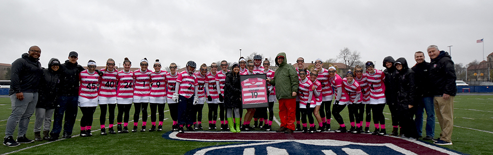 The women's lacrosse team honored Mark Misko, in the green coat, after his donation of pink uniforms for the team's annual Pink Game, which raises money to fight cancer.