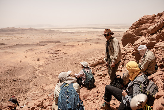 Group of students and professor Nizar Ibrahim on a hill in the Sahara, the vast ness of the desert behind them.