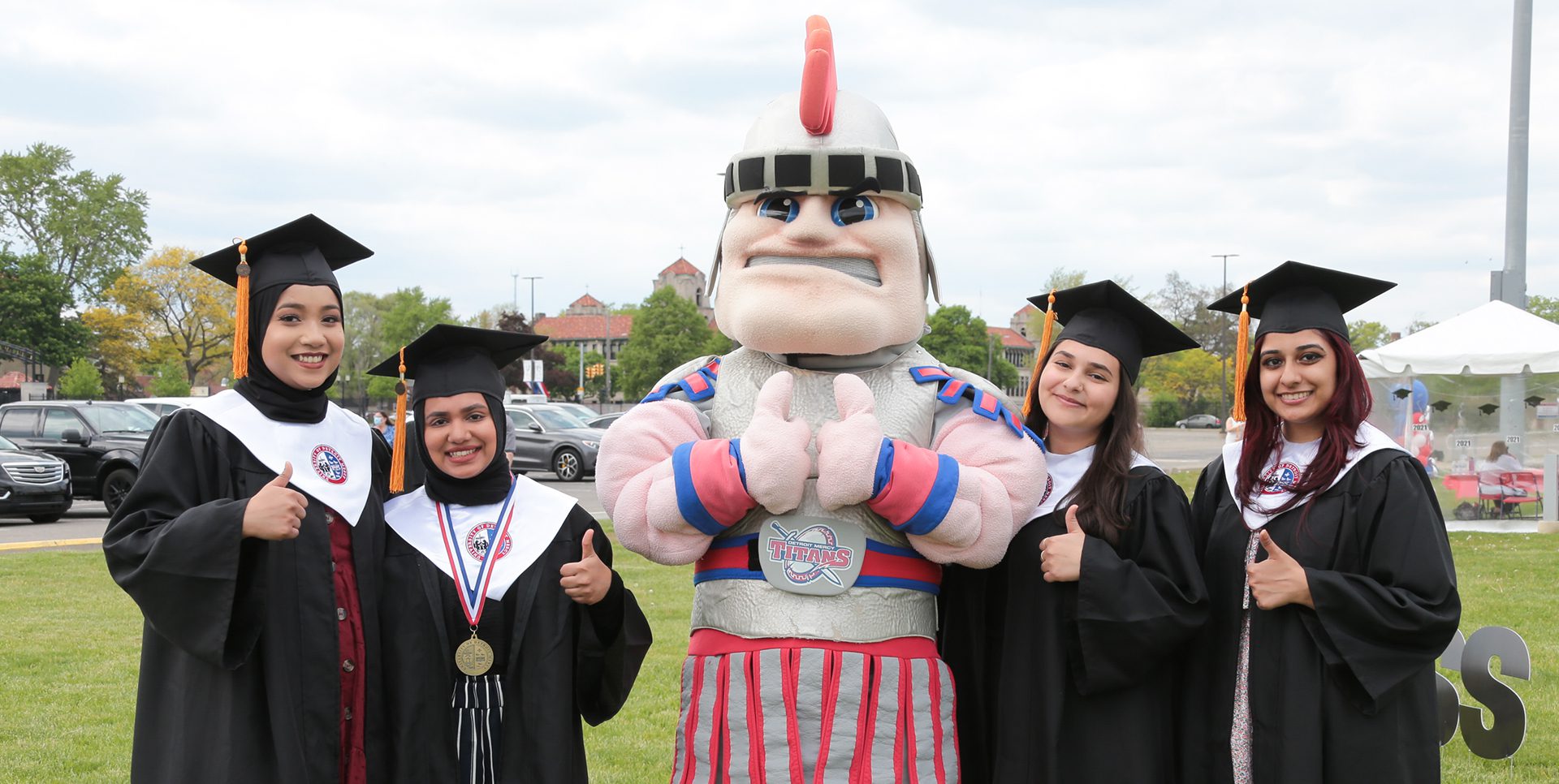 Four class of 2021 graduates poses with Tommy Titan.