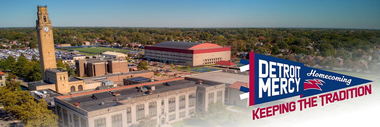 An aerial photograph of Detroit Mercy's McNichols Campus, with the Detroit Mercy Homecoming "Keeping the Tradition" pennant in the bottom right of the image.
