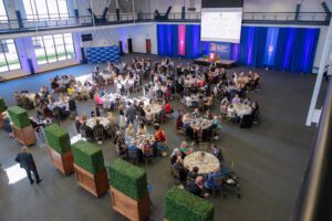 An overhead shot of 200 people having dinner at tables inside of the Student Fitness Center.
