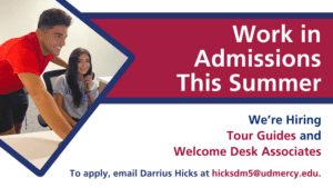 A graphic featuring two students in an office setting. Text reads, Work in Admissions This Summer, We're Hiring Tour Guides and Welcome Desk Associates, To apply, email Darrius Hicks at hicksdm5@udmercy.edu.