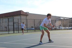 Two UDM students play tennis on the courts outside of the Student Fitness Center.