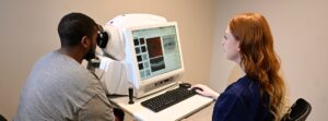 A technician uses a machine to look at the eyes of a patient inside of Detroit Mercy's Eye Institute.