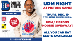 A flyer for UDM Night at Pistons Game. Takes place on Dec. 19 at 7 p.m. at Little Caesars Arena. There is a UDM/Pistons Hoodie giveaway and all you can eat seats available. On the left half of the page is a photo of a male wearing the hoodie. There are several logos inclduing Detroit Pistons and Utah Jazz logos as well as Detroit College Nights logo.