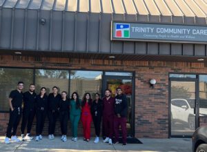 An image of a group of ten UDM nursing students standing outside the Trinity Healthcare clinic