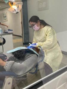 A woman works on a patient in a clinical setting.