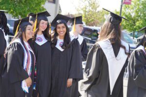 A graduate snaps a photo of three other classmates outdoors during 2025 Commencement.