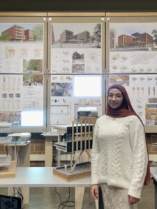 A student stands in front of her senior design project inside the School of Architecture and Community Development.