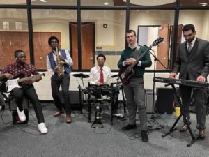 Five people play musical instruments inside of the Student Fitness Center.