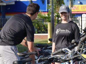 Two people stand outdoors amongst bicycles.