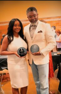 An image of two individuals holding award plaques.