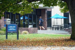 A student walks into the McNichols Campus Library on a fall day.