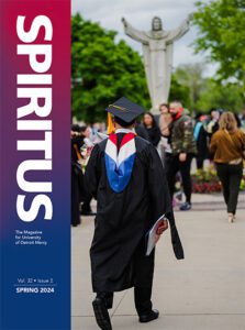 The front cover of the Spring 2024 issue of Spiritus, the magazine for University of Detroit Mercy. Volume 32, issue 2. The cover photo depicts students near the Jesus statue on the McNichols Campus at commencement.