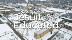An aerial photo of a snowy McNichols Campus in 2025, with text overlaying it and reading, 'We are Jesuit Educated.'