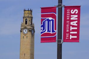 A photo of the banners on the light poles in front of the clock tower. The banners feature a UDM logo and one that reads, The World Needs Titans.