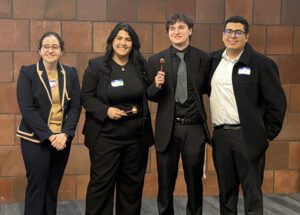 Four people stand and smile for a photo inside of the Student Union.