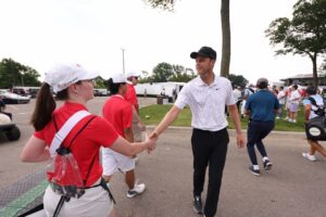An image of a golfer and tournament volunteers in red golf shirts.