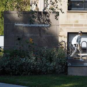A student walks into the Warren Loranger Architecture Building on a fall day.