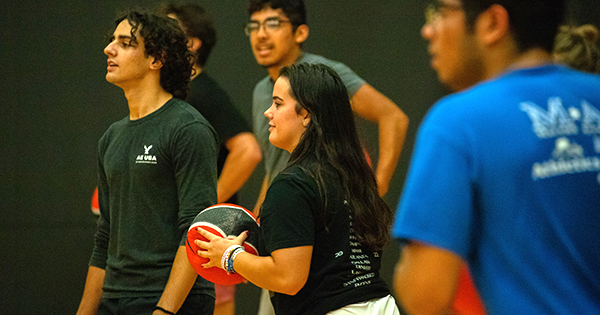 students playing dodgeball highlighting the girl in the center holding hte ball