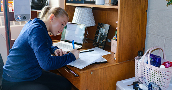 female student studying or taking notes in her dorm room.
