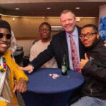 Four people pose for a photo, while smiling, inside of the Titan Club.